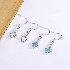 Detailansicht der herzförmigen Ohrhänger mit blauen und weißen Kristallen in Silber