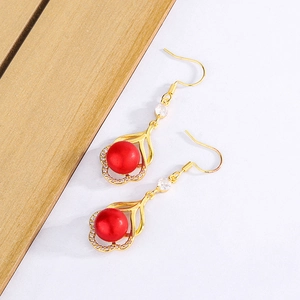 Vue détaillée des boucles d'oreilles perles rouges avec crochets dorés et zircons