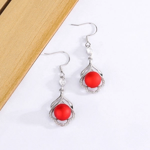 Détail de boucles d'oreilles perles rouges avec cadre fleuri argenté et zircons