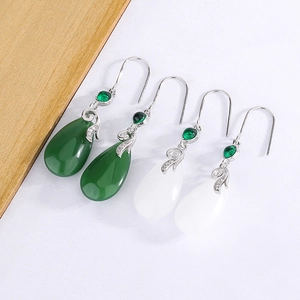 Detail of vintage teardrop earrings in emerald green and milky white jade finish