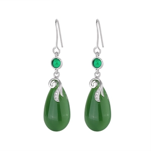 Detail of vintage teardrop jade earrings with intricate silver floral filigree settings