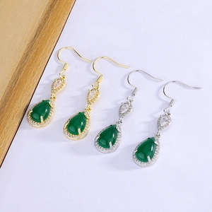 Detail of vintage teardrop earrings with green emerald-cut stones and zircon accents
