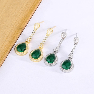 Detail of teardrop green emerald earrings in gold and silver plating with zircon accents