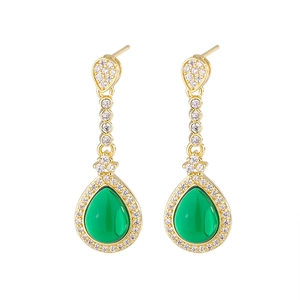 Detailed macro of gold drop earrings with green teardrop stones and pavé accents