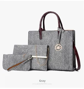 Detailed view of 3-piece grey tote set with wine red handles and golden leaf charm