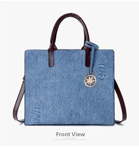 Close-up of blue denim tote bag with vintage distressed details and brown leather handles