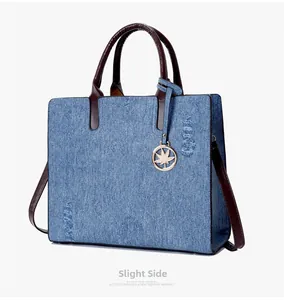 Detailed close-up of blue denim tote bag with distressed details and brown leather handles