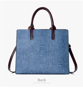 Back view of a large denim tote bag featuring retro distressed texture and brown leather straps