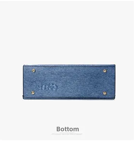 Close-up of washed blue denim tote base with protective gold metal feet and rivets