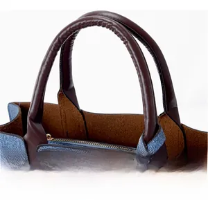 Detail of blue denim fabric tote bag with brown leather handles and golden zipper