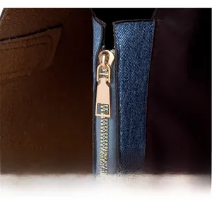Detail of premium golden metal zipper and blue denim texture on large tote bag