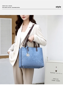 Detail of blue denim textured handbag with gold leaf pendant and adjustable strap