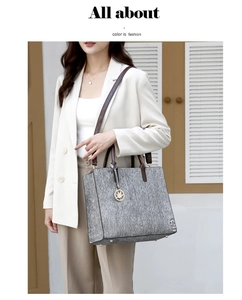 Detail of grey fabric tote with brown leather handles and gold maple leaf pendant