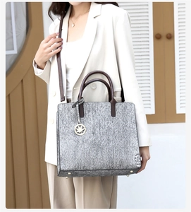 Close-up of large tote bag with grey textured weave and brown leather handles