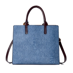 Light blue distressed denim tote bag with brown leather handles and adjustable shoulder strap