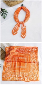 Detail of orange satin square scarf featuring white floral and paisley patterns