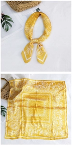 Detailed flat lay of a yellow silk square scarf with vintage white paisley and floral prints