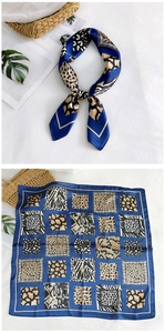 Detailed view of a knotted silk scarf featuring leopard and zebra patterns with blue borders