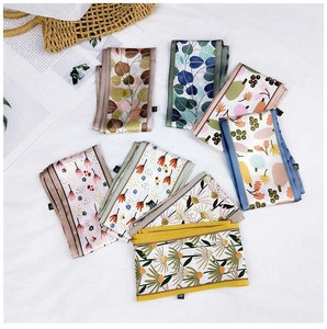 Flat lay of multiple floral print twilly scarves with botanical patterns on white fabric