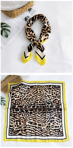 Detail of leopard print silk scarf with striped borders on white textured background