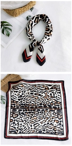 Detail view of square silk scarf with leopard print and elegant red and black striped borders