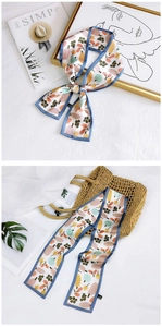 Detailed view of floral polyester neck scarf tied in a bow next to fashion accessories