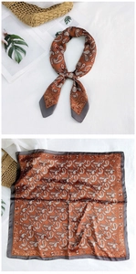 Detail of a brown silk-feel paisley square scarf featuring elegant white patterns and grey borders