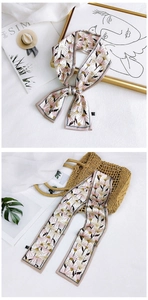Detail of floral silk scarf tied on a straw bag and styled with a minimalist magazine backdrop