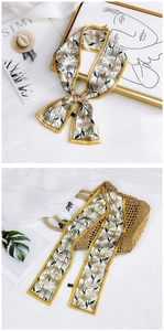 Detailed shot of floral daisy twilly silk scarf tied on a straw handbag with yellow piping