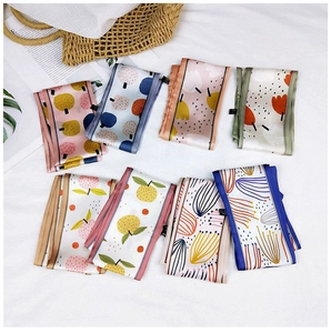 Flat lay of seven long floral silk scarves with various patterns and vibrant colors