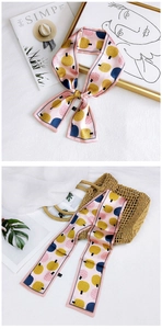 Detail of pink floral twilly scarf styled as a bow and draped on a straw bag