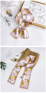Floral pink silk scarf with yellow tulips and black polka dots tied on a straw tote bag