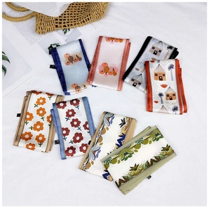 Detailed flat lay of eight multi-patterned floral silk twilly scarves with decorative props