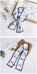 Detail of floral skinny scarf tied on a straw bag and styled with artistic props
