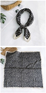 Close-up of black and white polka dot silk scarf with elegant cream-colored border