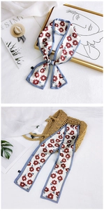 Detailed texture of satin floral scarf featuring red flowers and light blue borders