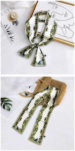 Detailed shot of double-sided floral twilly scarf with green leaf patterns and labels