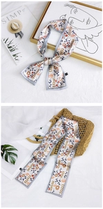 Detail of floral skinny scarf with orange flowers and gray berries on a straw bag