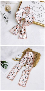 Detailed view of floral silk scarf with mushroom prints styled on a straw bag
