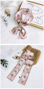 Detail of champagne pink twilly silk scarf with umbrella pattern tied on a handbag