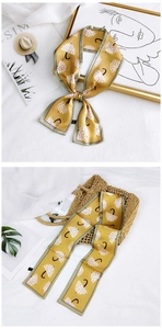 Detail of floral umbrella print on yellow silk scarf tied to a straw handbag strap
