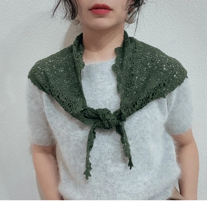Detail of dark green lace crochet triangle scarf styled over a grey plush sweater