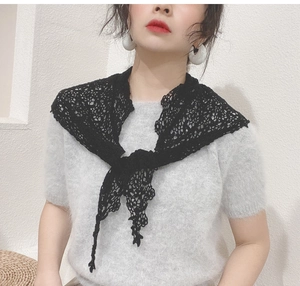 Detail of elegant black lace crochet shawl with floral patterns over a grey mohair sweater