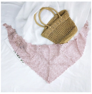 Detailed texture of pink floral lace triangle scarf paired with a woven straw handbag
