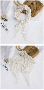 Detailed view of white lace floral triangle scarf with hollow knit texture and tassels