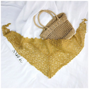 Close-up of ginger yellow lace triangle scarf with hollow floral crochet patterns