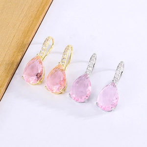 Detail of teardrop pink zircon earrings in gold and silver finish with crystal inlay