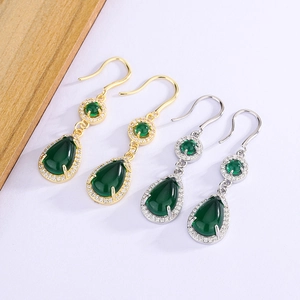 Close-up of vintage teardrop emerald earrings in gold and silver settings with zircon