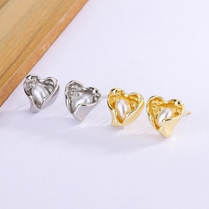 Close-up of irregular gold and silver heart stud earrings with teardrop pearls