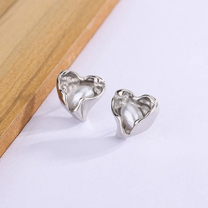 Detailed view of silver heart stud earrings with white pearl inlay and wavy texture